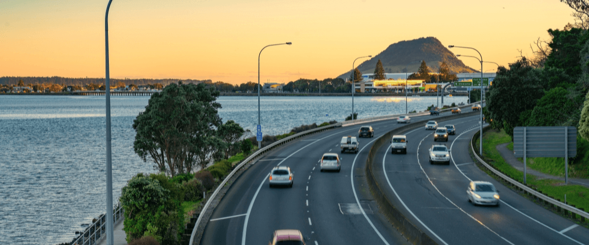Coastal road beside Tauranga Harbour with Mount Maunganui at sunset — The Gold House® gold and silver bullion, New Zealand