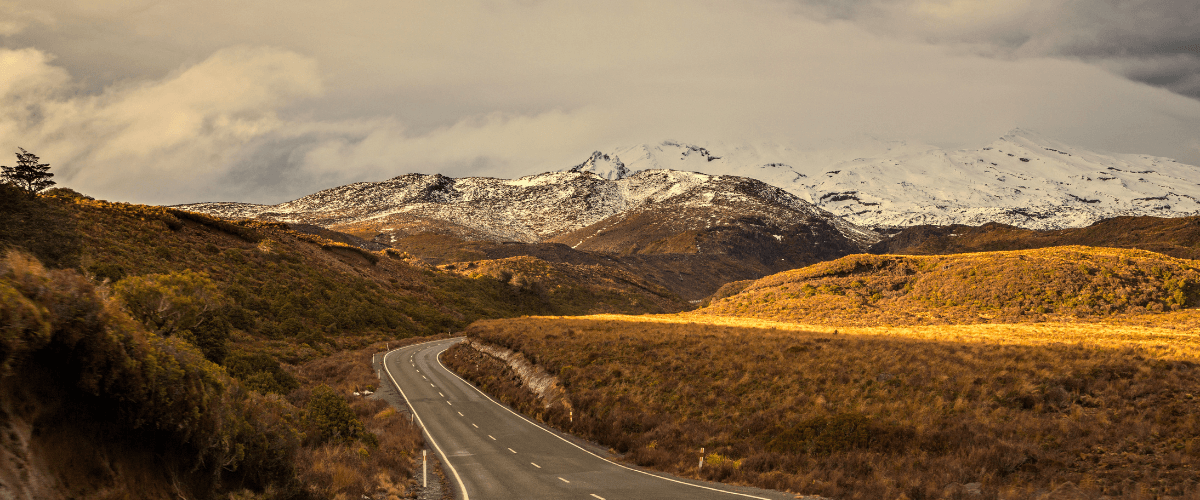 Scenic mountain road through New Zealand high country at golden hour — The Gold House® bullion and treasury building, New Zealand