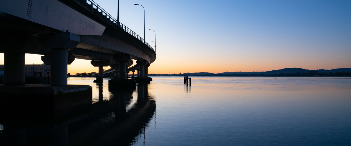 The Gold House® — Tauranga harbour bridge at twilight, New Zealand Twilight panorama of a Tauranga harbour bridge over calm reflective water — The Gold House® precious metals brokerage, Bay of Plenty, New Zealand